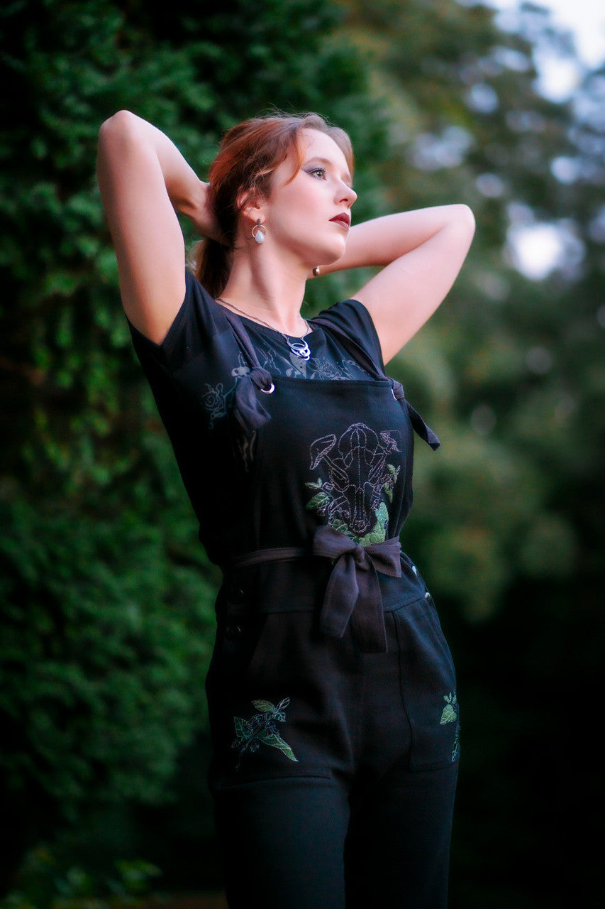 Woman posing with arms near head wearing Forest Burial Overalls.