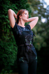 Woman posing with arms near head wearing Forest Burial Overalls.