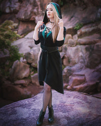 Woman posing on rocks, showing side view of the Dahlia Hooded Dress wearing oversized hood paired with tights.