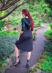 Woman posing showing oversized hood on the Dahlia Hooded Dress surrounded by trees.