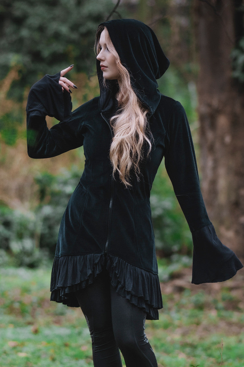 Model posing in woods showing front of the Occultist Coat with it's draping sleeves zipped up.