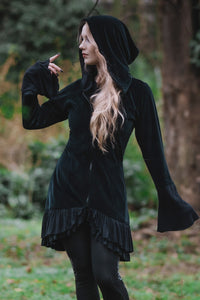 Model posing in woods showing front of the Occultist Coat with it's draping sleeves zipped up.