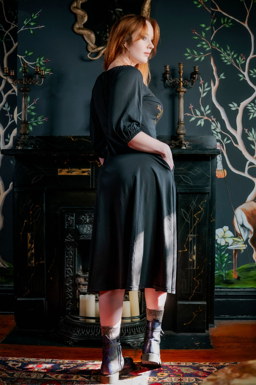 Model posing in black Persephone  Summer dress showing back of dress and inseam pockets.