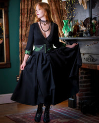 Forager Skirt in black model is wearing herbalist belt and holding the skirt out with one hand