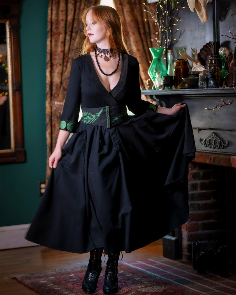 Forager Skirt in black model is wearing herbalist belt and holding the skirt out with one hand